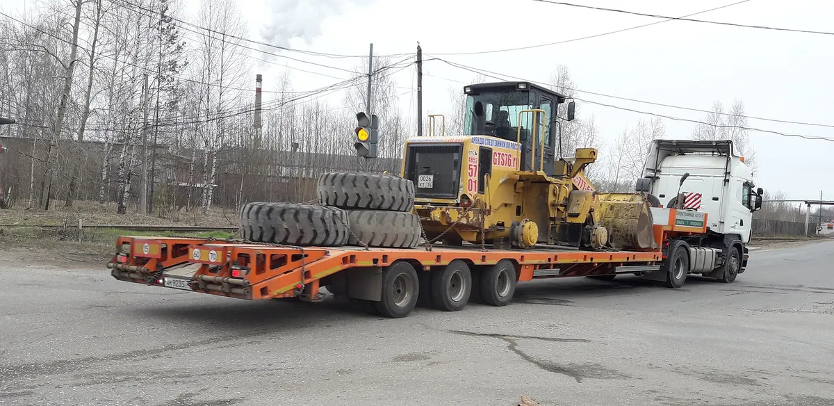 Tieflader mit verladener Baumaschine auf dem Betriebshof